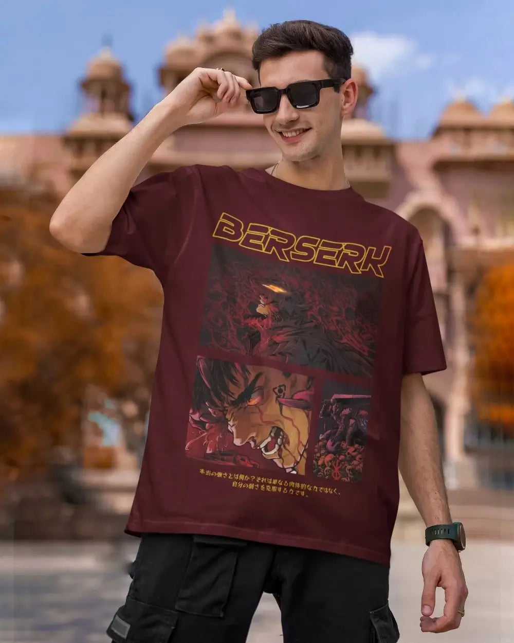 Person wearing a 'Berserk' oversized maroon t-shirt with a graphic design in an outdoor setting.