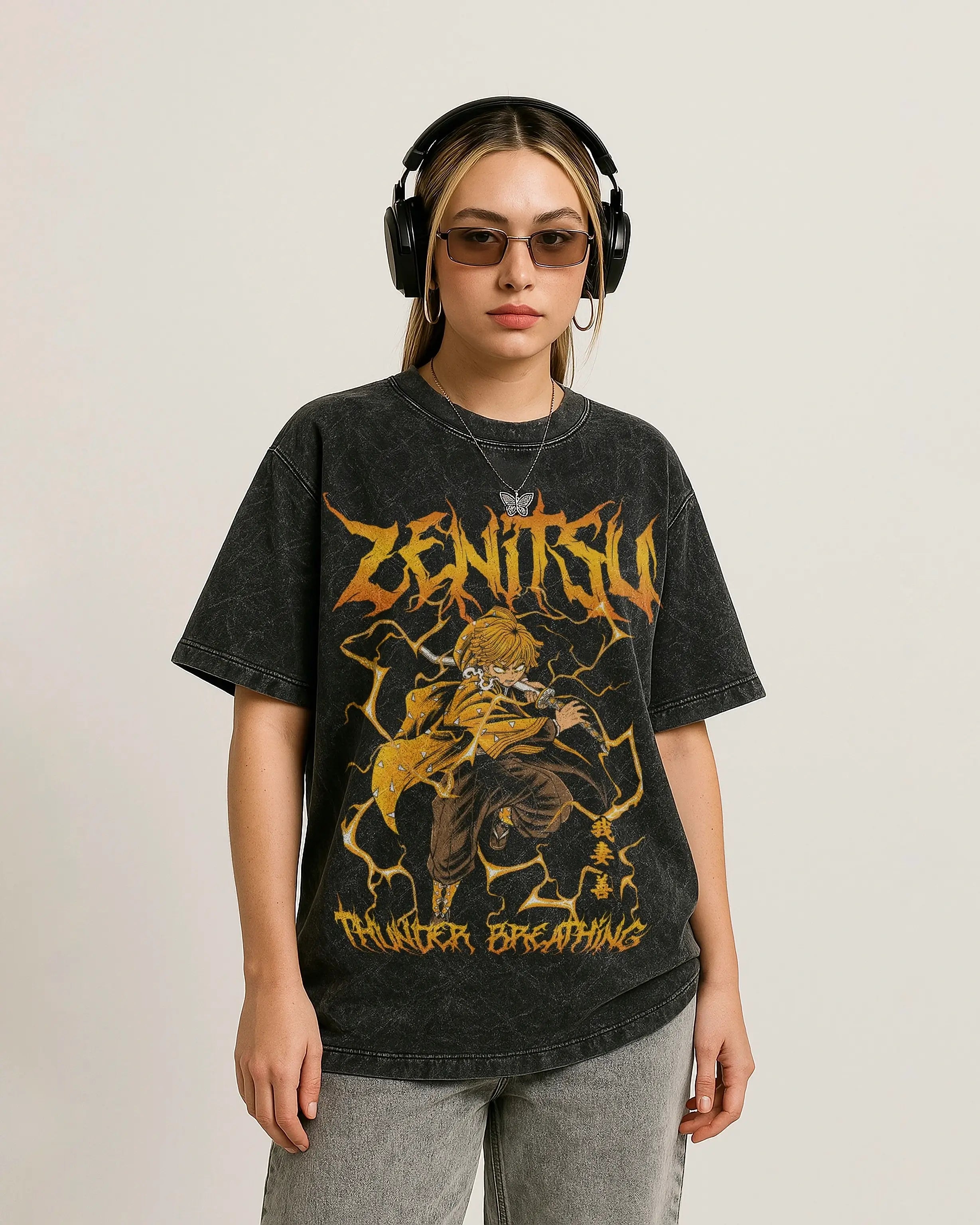 model wearing a acid wash oversized t-shirt with graphic design of zenitsu from demon slayer with text, headphones, and sunglasses on a plain background