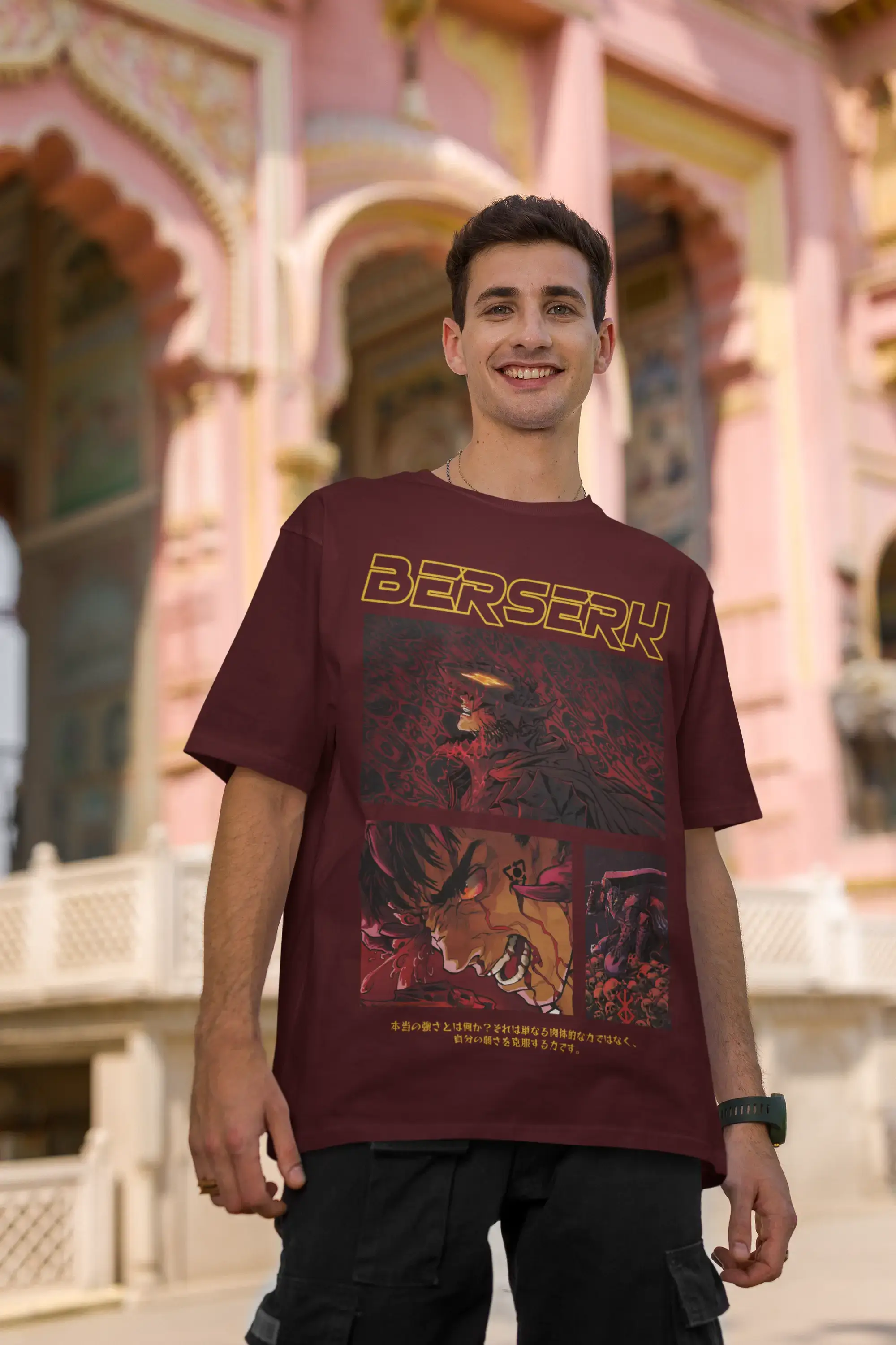 Person wearing a maroon oversized t-shirt with 'Berserk' graphic design in front of a colorful architectural background.